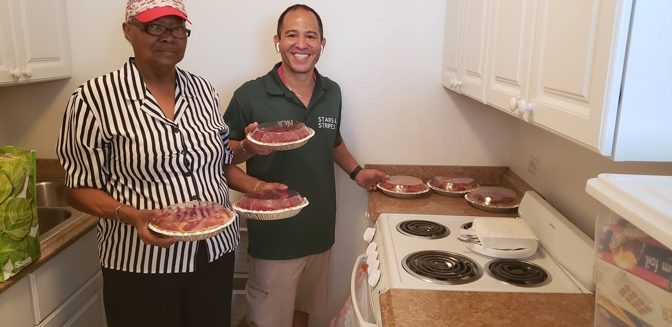 Stars and Stripes mover smiling with senior customer holding pies